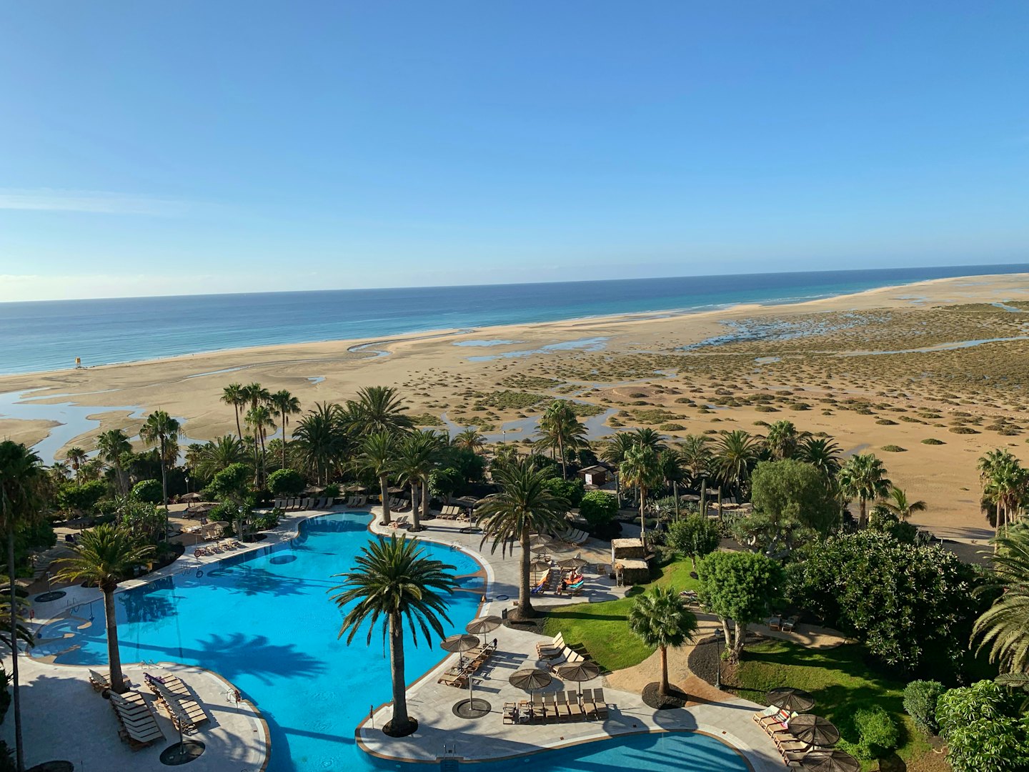 Tropical resort pool area overlooking a sandy beach and ocean.