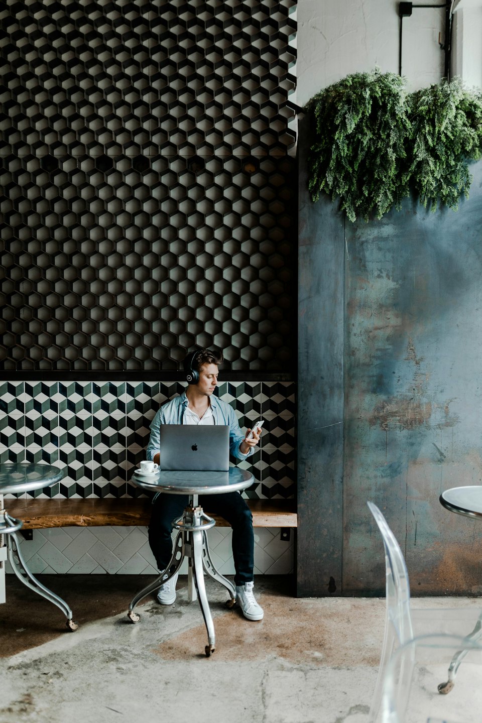 Man working on laptop and phone in a modern cafe.
