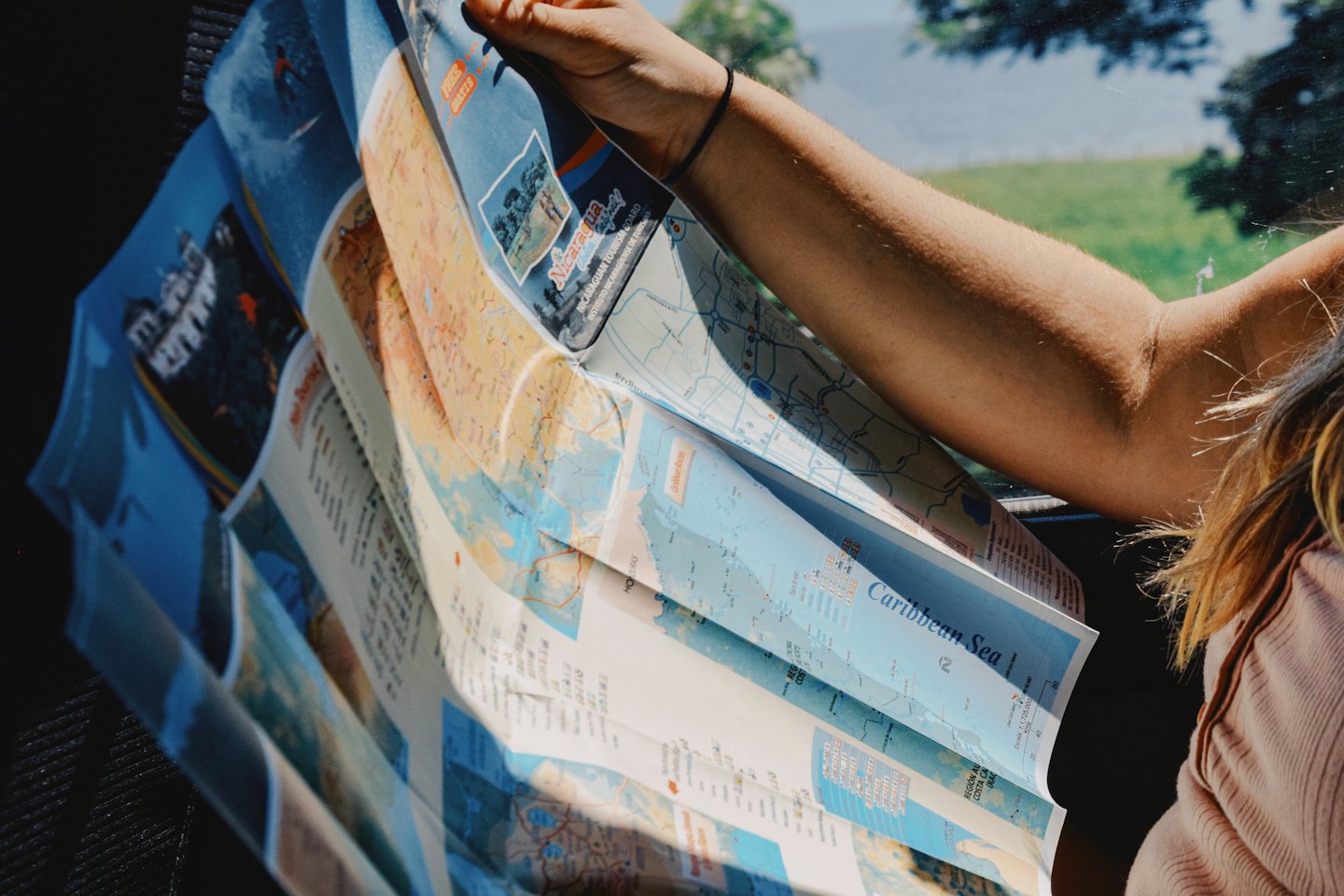 Person unfolding travel maps in a car.